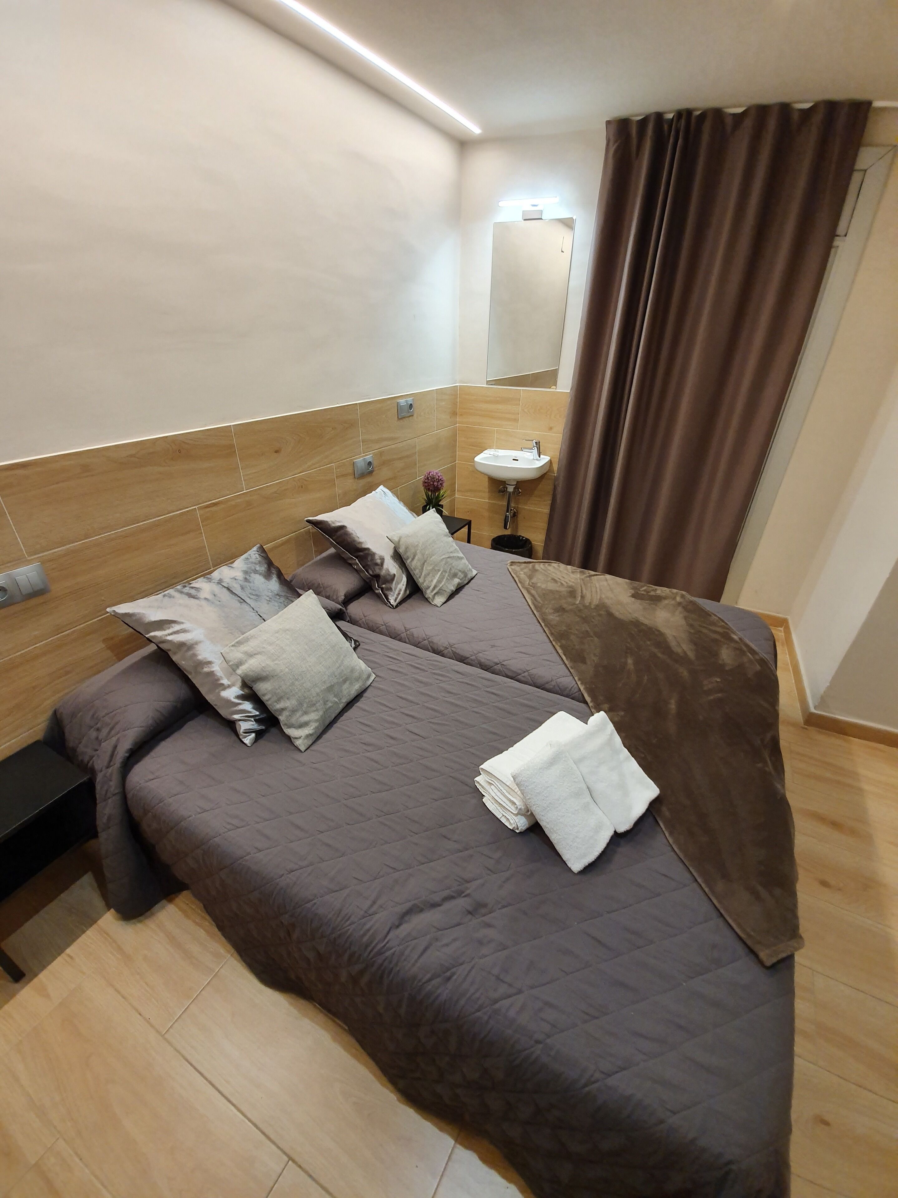 Een hotelkamer met een groot bed, een nachtkastje, een kleine badkamer met een wastafel en een spiegel.