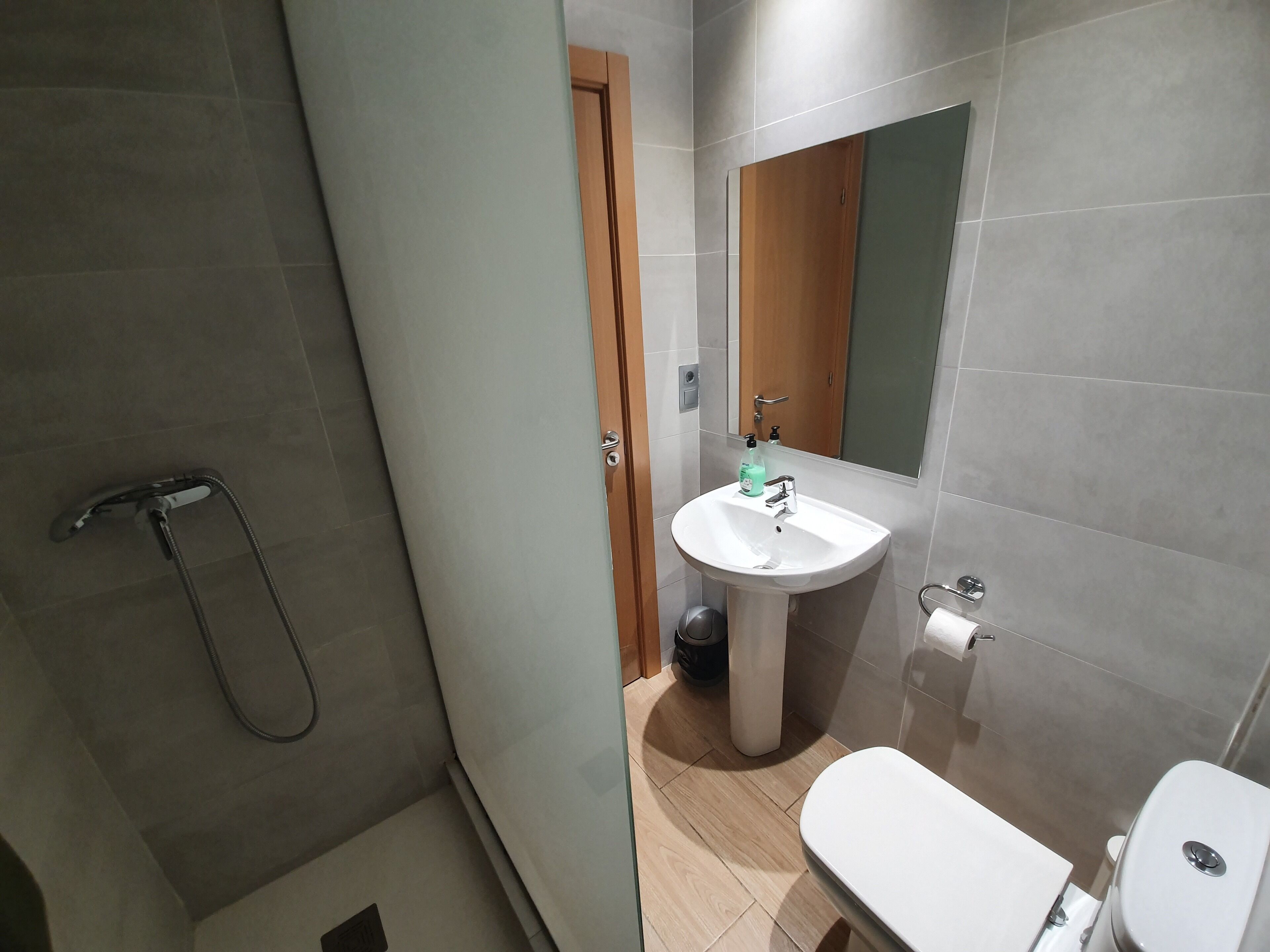 A modern bathroom with a shower, sink, and toilet.