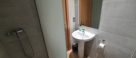 A modern bathroom with a shower, sink, and toilet.