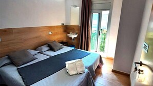 A modern hotel room with a large bed, a bedside table, a mirror, and a view of the outdoors. - Hostal Sant Ramón (Barcelona)