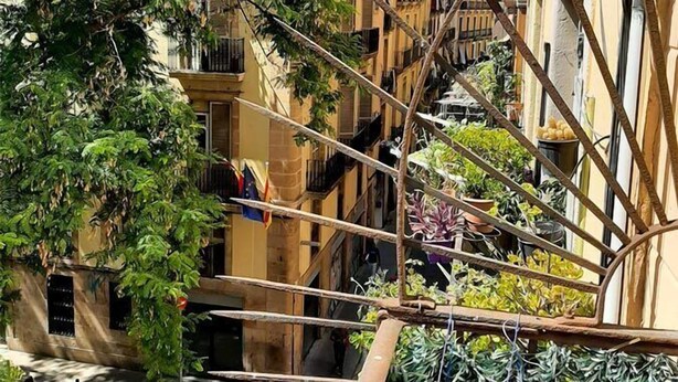 A narrow urban street with buildings on either side, a staircase, and a tree with hanging laundry. - Hostal Sant Ramón (Barcelona)