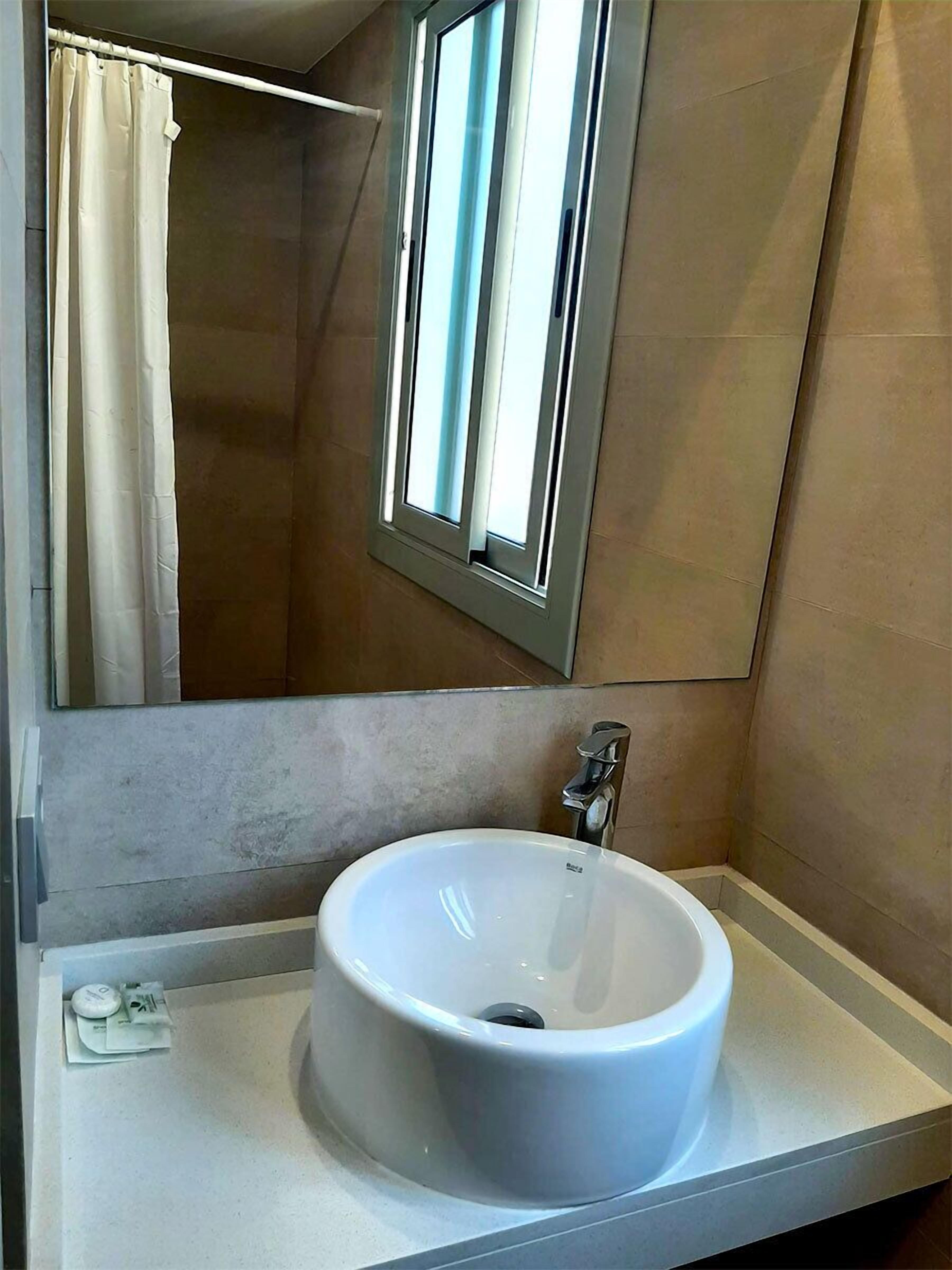 Une salle de bain avec un lavabo blanc, un miroir et un rideau de douche.