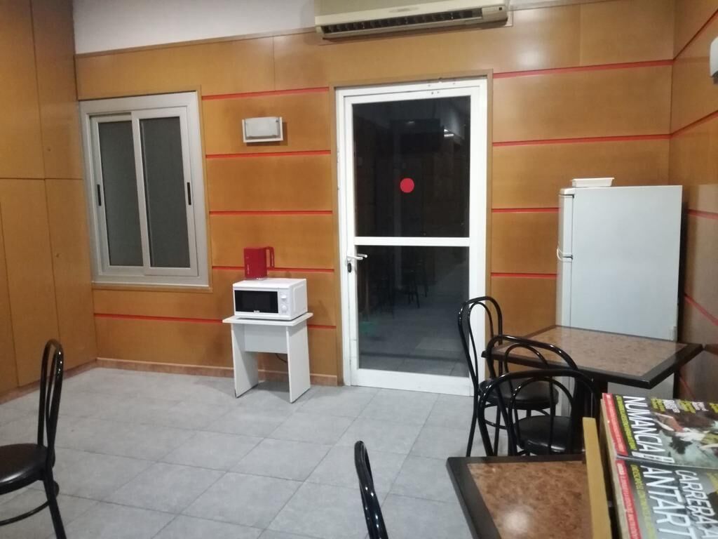 Une chambre dotée d’une porte coulissante, d’un four à micro-ondes, d’une petite table et d’une chaise.