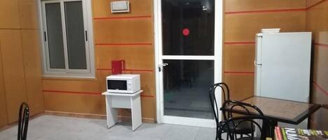 A room with a sliding door, a microwave, a small table, and a chair.