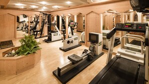 A gym with various exercise machines, wooden walls, and a ceiling with recessed lighting.