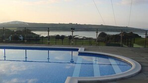 A swimming pool with a view of a body of water and hills in the background.