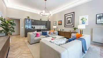Een moderne woonkamer met een grijze zithoek, een salontafel en een keuken op de achtergrond.