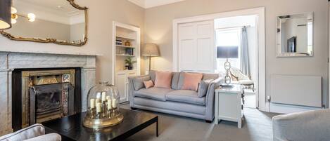 A living room with a fireplace, a sofa, a coffee table, and a lamp.