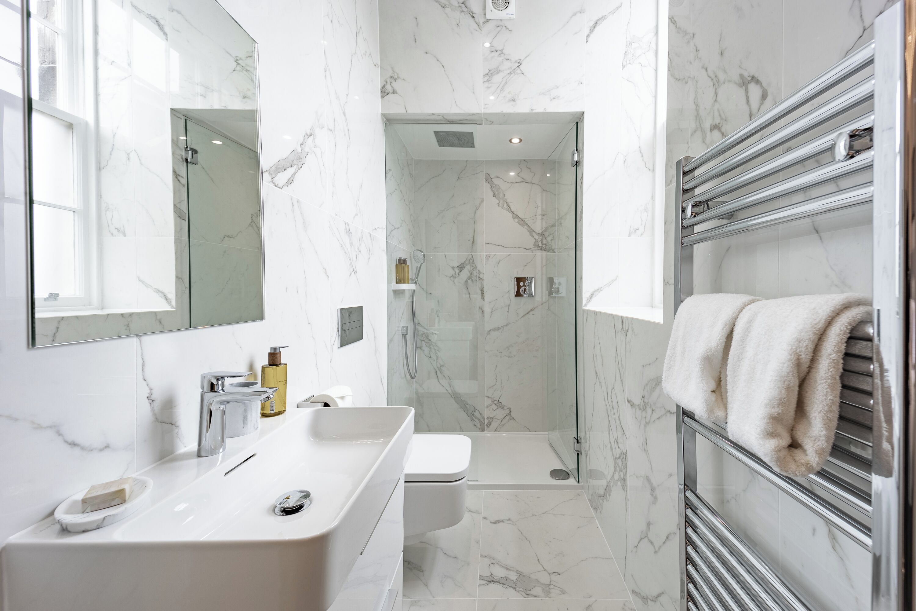 Un bagno moderno con un lavabo in marmo, una cabina doccia in vetro e un porta asciugamani.