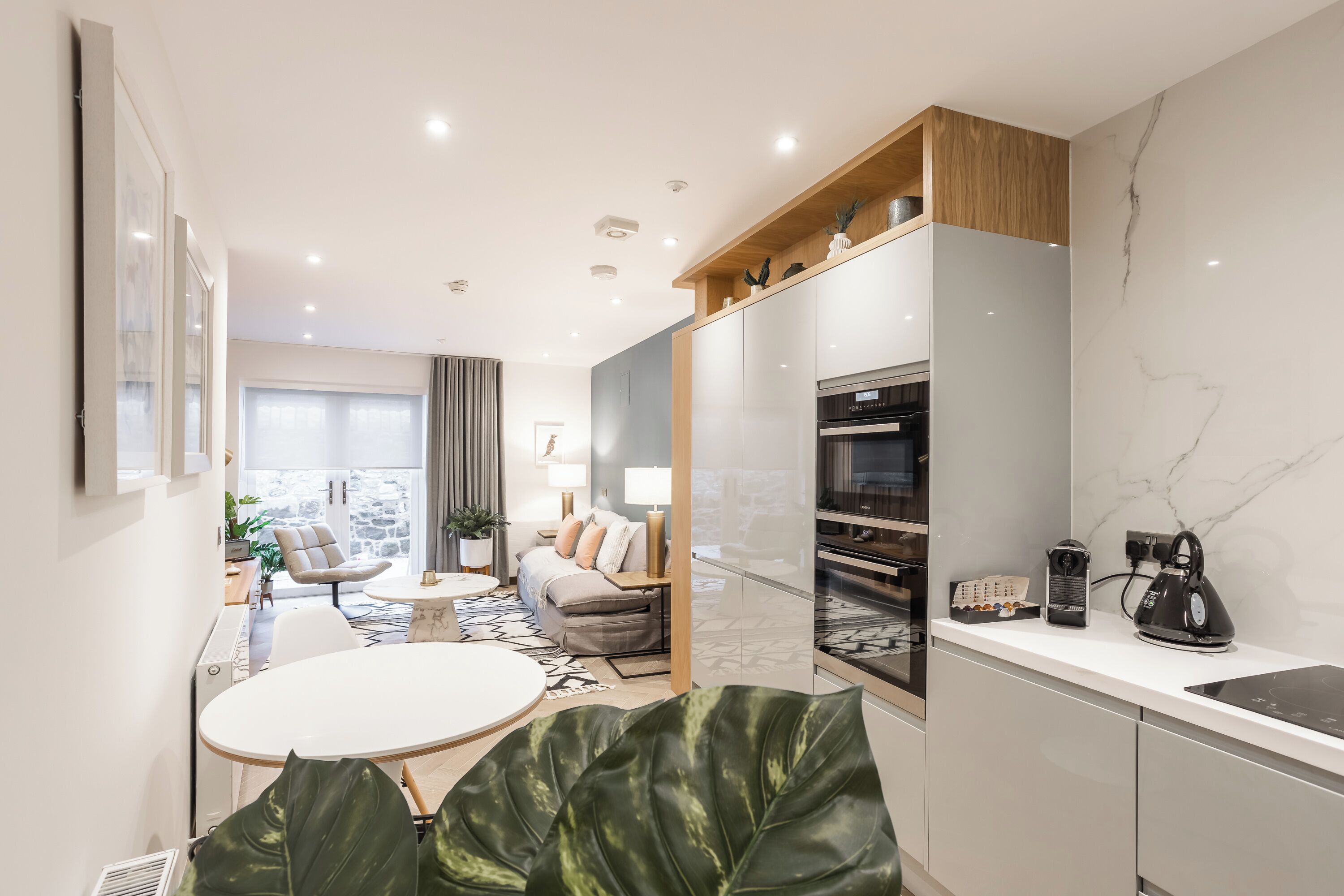 A modern kitchen with a built-in oven, a coffee machine, and a kettle on the counter.