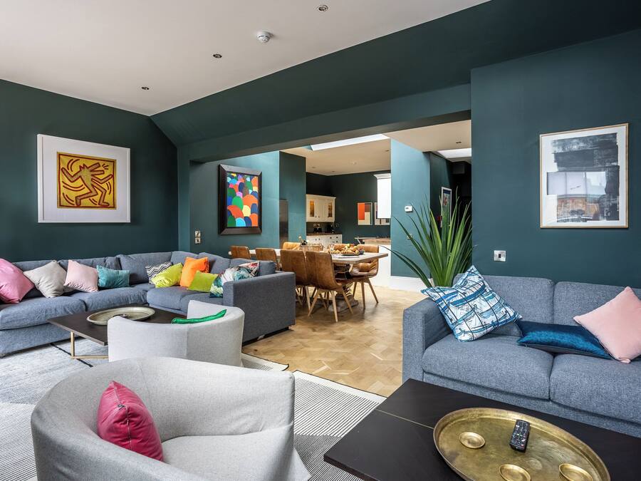 A modern living room with a grey sofa, a grey armchair, and a coffee table with a remote control.