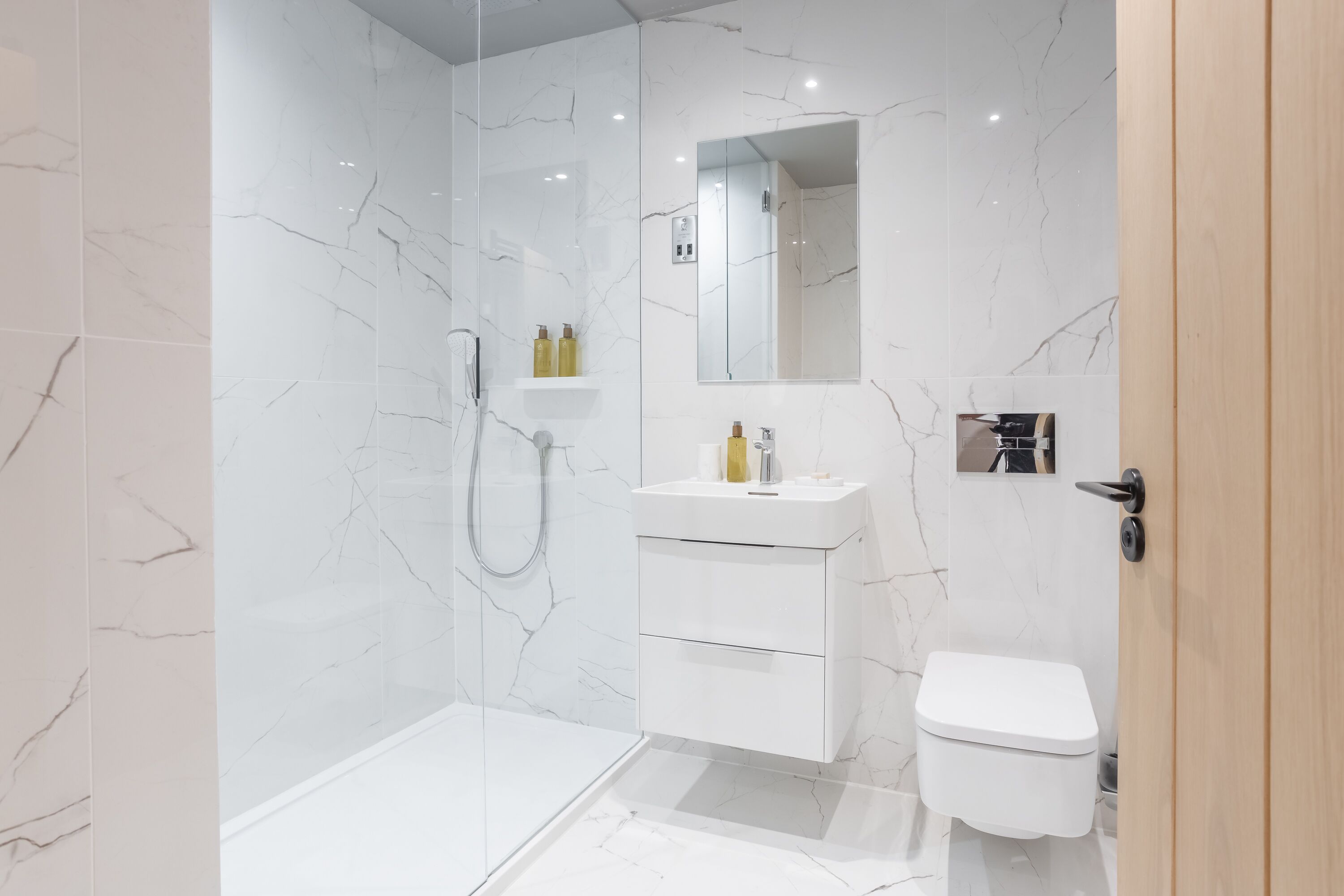 A modern bathroom with a glass-enclosed shower, a white vanity with a mirror, and a toilet.