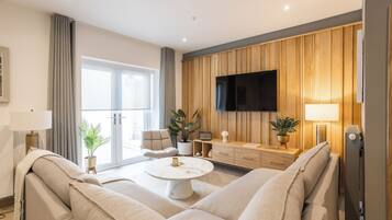 A modern living room with a sofa, a coffee table, a TV, and wooden paneling on the wall.