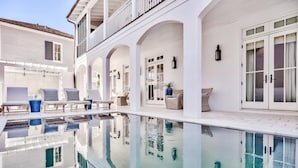 Ett poolområde med solstolar och ett pool med klart vatten.