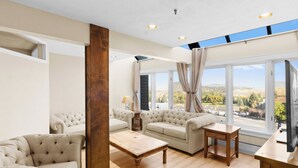 Ein geräumiges Wohnzimmer mit großem Fenster, einem Holztisch und einer Couch.