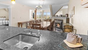 Eine moderne Küche mit Granit-Arbeitsplatten, einer Edelstahl-Spüle und einem Essbereich mit Kamin.