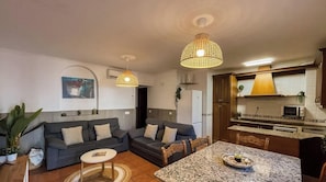 A compact living space with a sofa set, a dining table, and a kitchen area.
