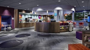 A modern reception area with a central counter, seating, and a view of the outdoors. - TRU by Hilton Perrysburg Toledo, OH (Perrysburg)