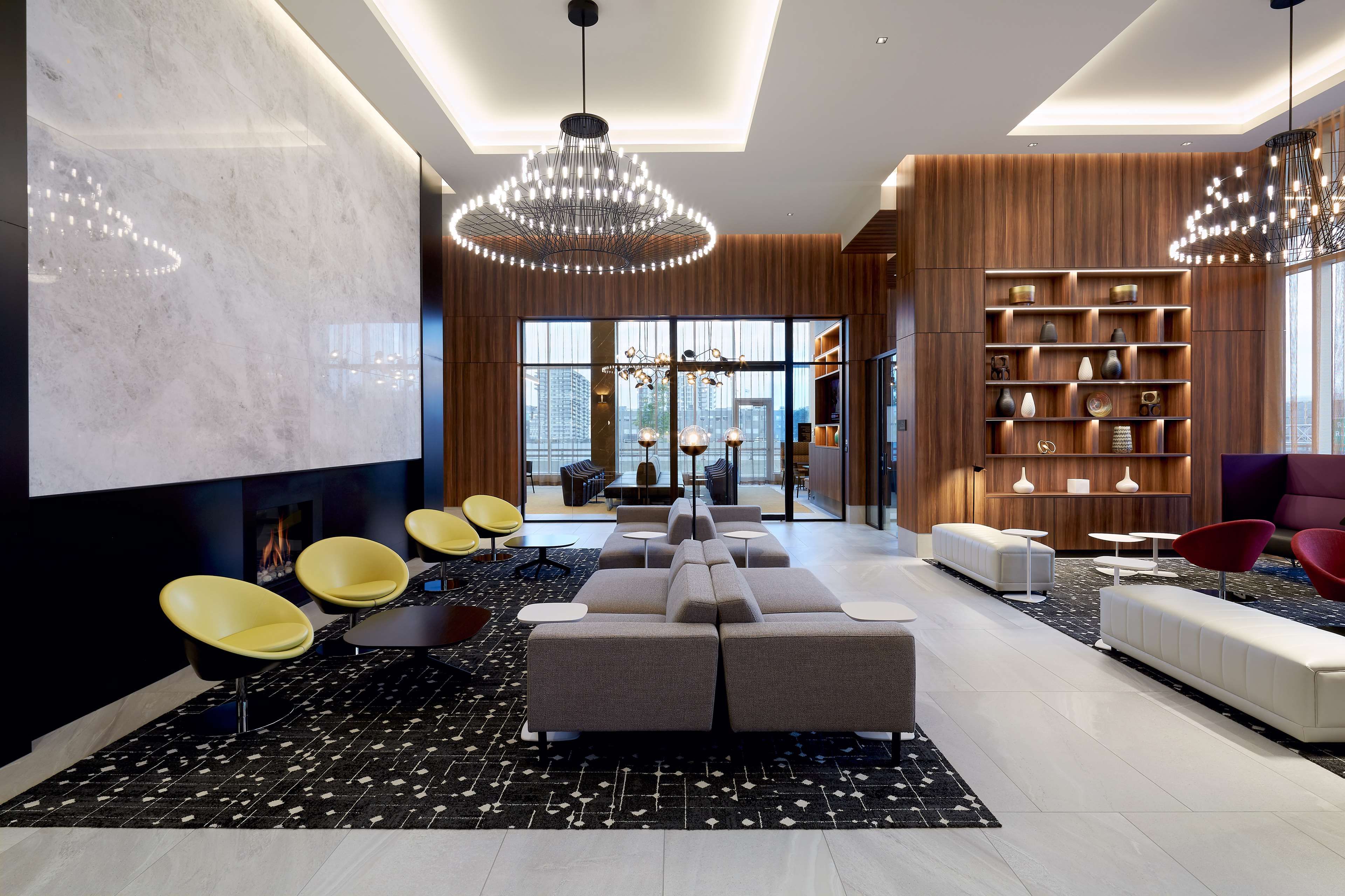 A modern interior with a seating area, a fireplace, and a view of the city.