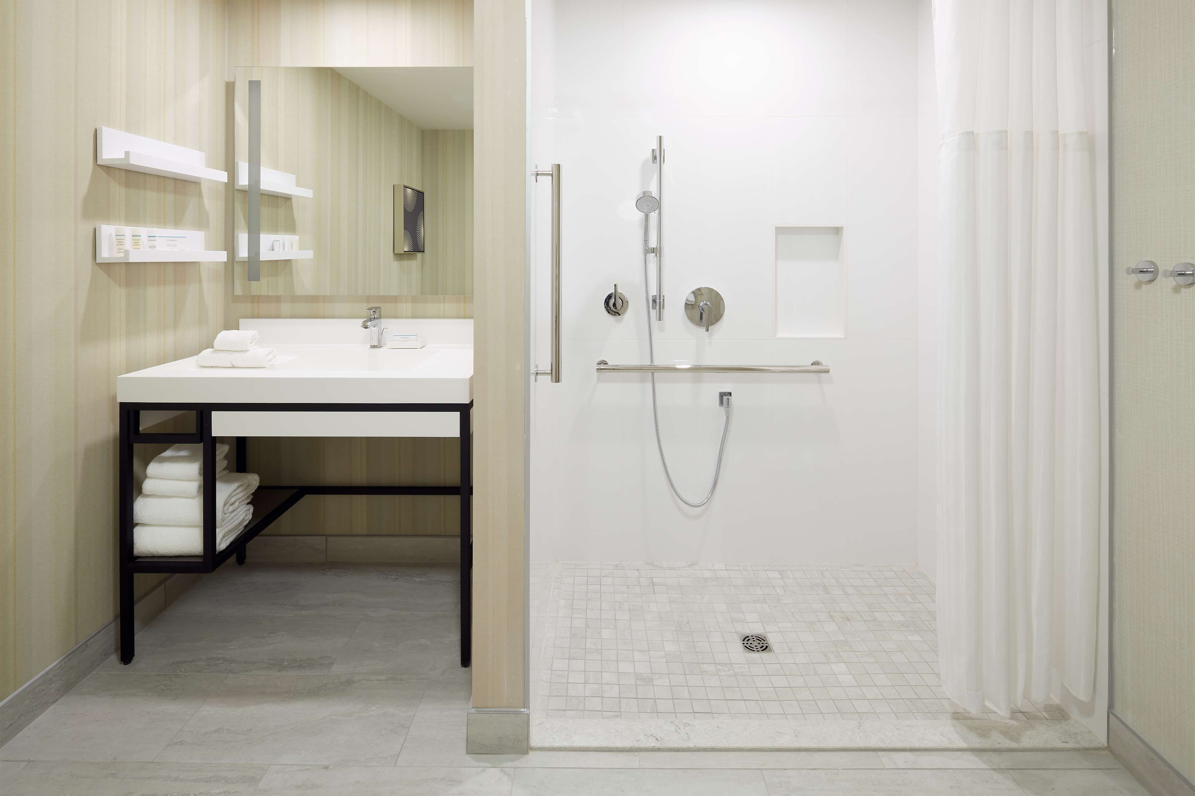 A modern bathroom with a white sink, mirror, and shower.