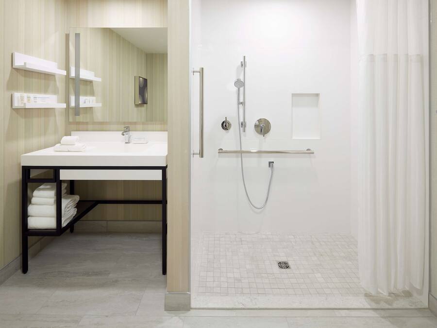 A modern bathroom with a white sink, mirror, and shower.