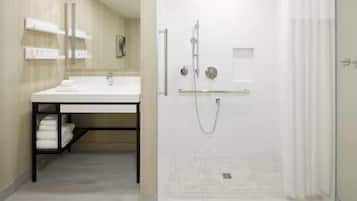 Un baño moderno con ducha, lavabo con espejo y un perchero para toallas.