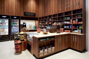 A café with a wooden interior, a refrigerated display case, and a variety of snacks and beverages. - Hilton Garden Inn Montreal Midtown (Montreal)