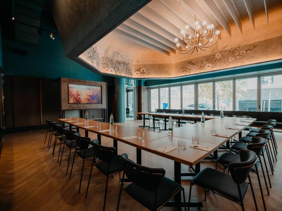 Uma sala de conferências com uma mesa comprida, cadeiras e uma janela grande.