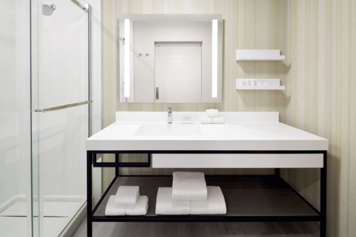 A modern bathroom with a white sink, a mirror, and a glass shower enclosure.