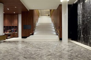 A modern interior with a marble staircase, wooden paneling, and a large black marble wall. - Hilton Garden Inn Montreal Midtown (Montreal)