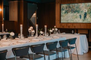 A dining area with tables set for a meal, featuring tall candles, white tablecloths, and dark chairs. - Hilton Garden Inn Montreal Midtown (Montreal)