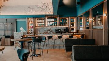 Una zona de bar moderna con mostrador de mármol, taburetes y una variedad de botellas y vasos.