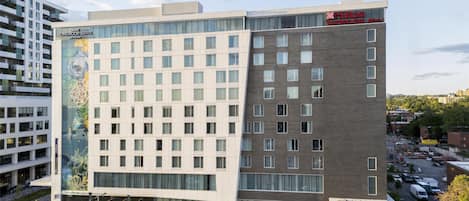 A modern hotel building with multiple floors, large windows, and a prominent garden hotel sign.