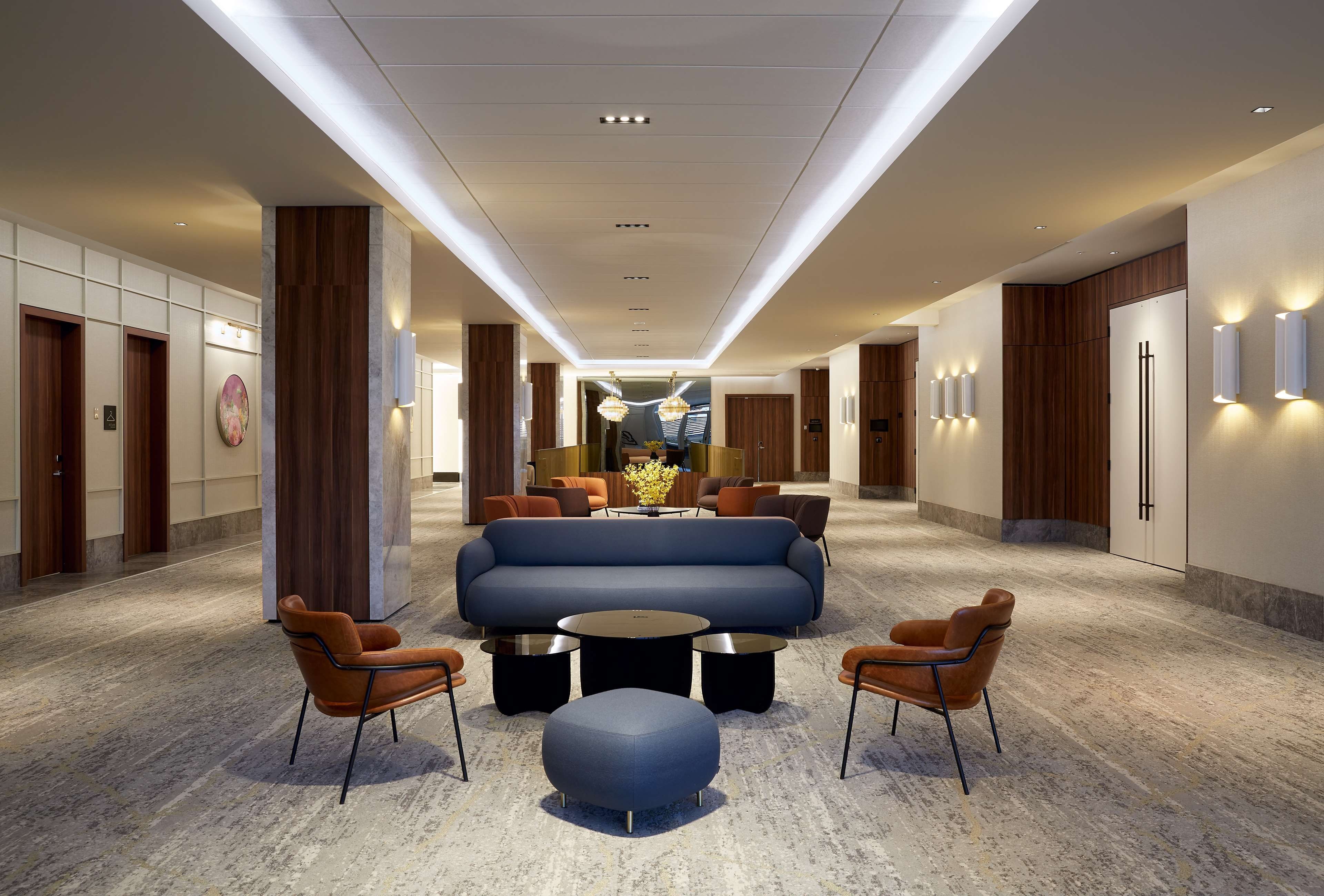 Un vestíbulo de hotel con una zona de estar central, una recepción y un diseño moderno.