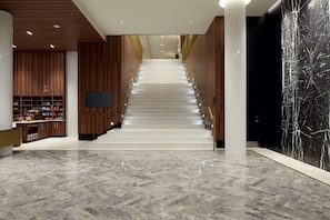 Ein modernes Interieur mit einer Marmortreppe, Holzvertäfelung und einer großen schwarzen Marmorwand.