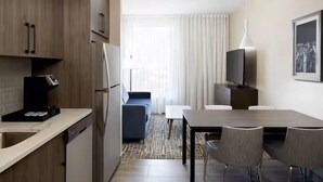 Ein kompaktes Hotelzimmer mit Küchenzeile, Essbereich und Sitzgelegenheit.