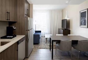 Habitació d'hotel compacta amb petita cuina, zona de dinar i espai per seure.