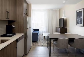 Habitación de hotel compacta con kitchenette, zona de comedor y espacio de descanso.
