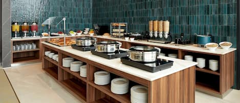 A buffet setup with multiple serving stations, including hot and cold food options, and a variety of condiments and beverages.
