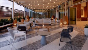 Un área de lounge moderna al aire libre, con disposición de asientos, una mesa de centro e iluminación ambiental.