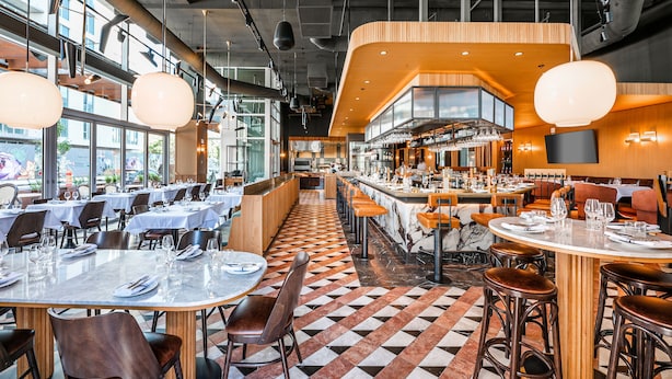 Un restaurante moderno con suelo a cuadros, varias mesas para comer y una zona de bar.