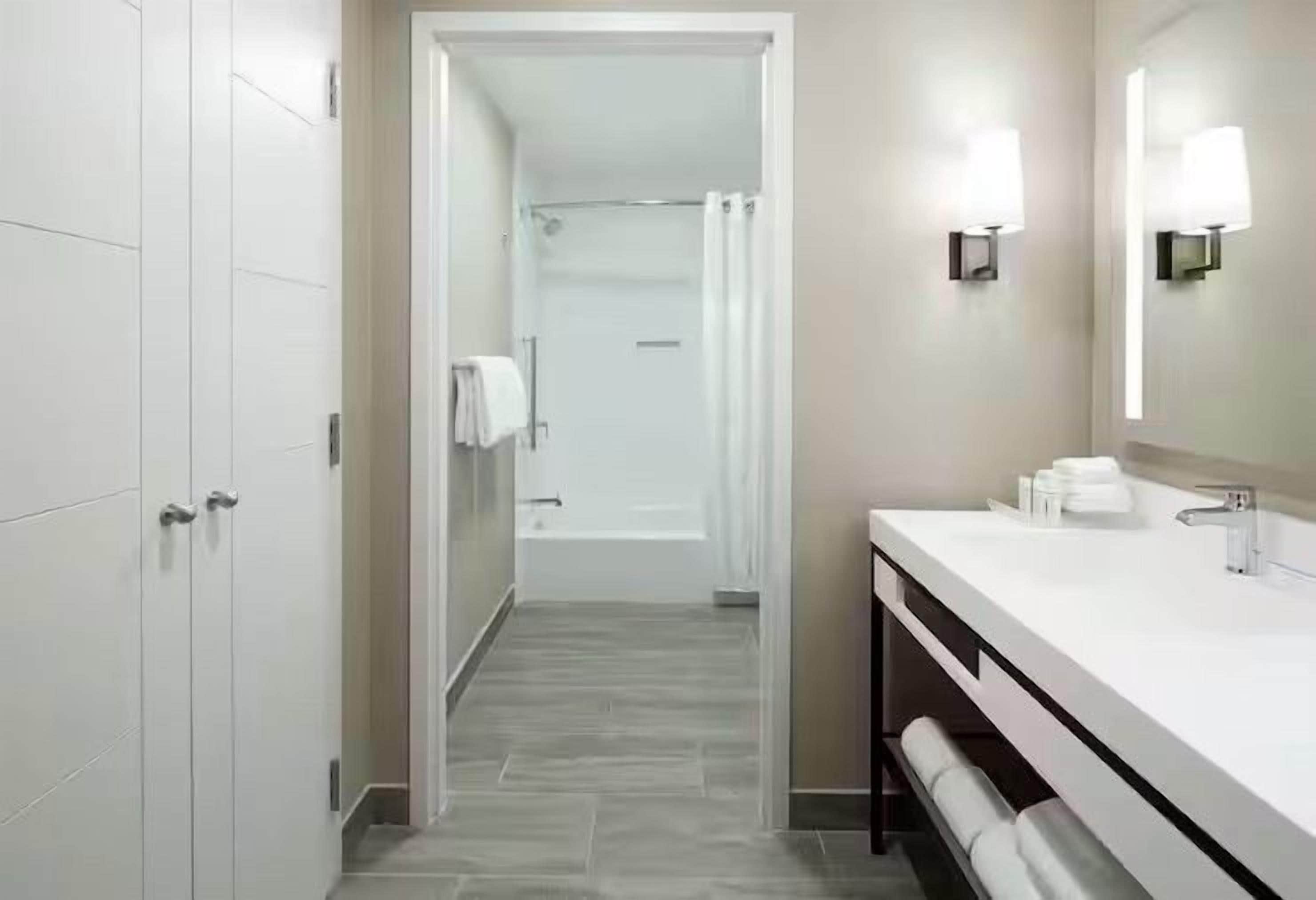 A modern bathroom with a shower, a vanity with a mirror, and a towel rack.