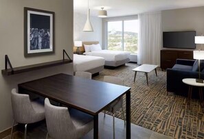 Habitación de hotel con una cama, un escritorio, una silla, un televisor y una ventana con vistas.