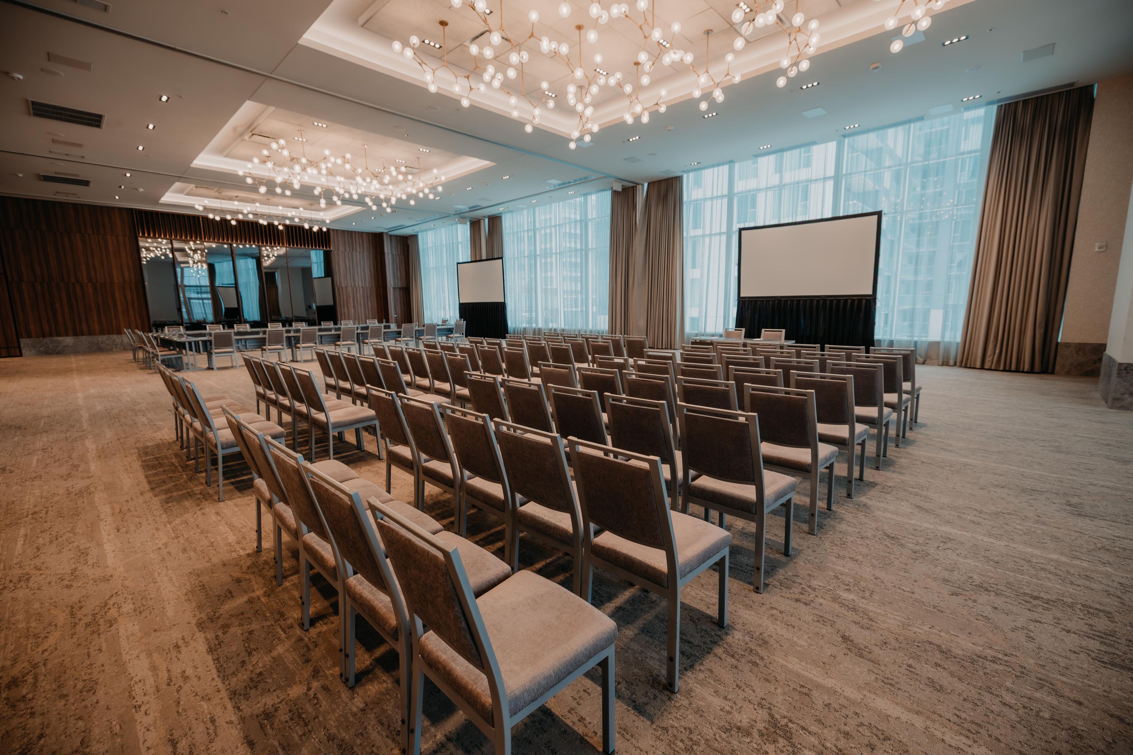 Une salle de conférence avec des rangées de chaises, un grand écran et un projecteur.