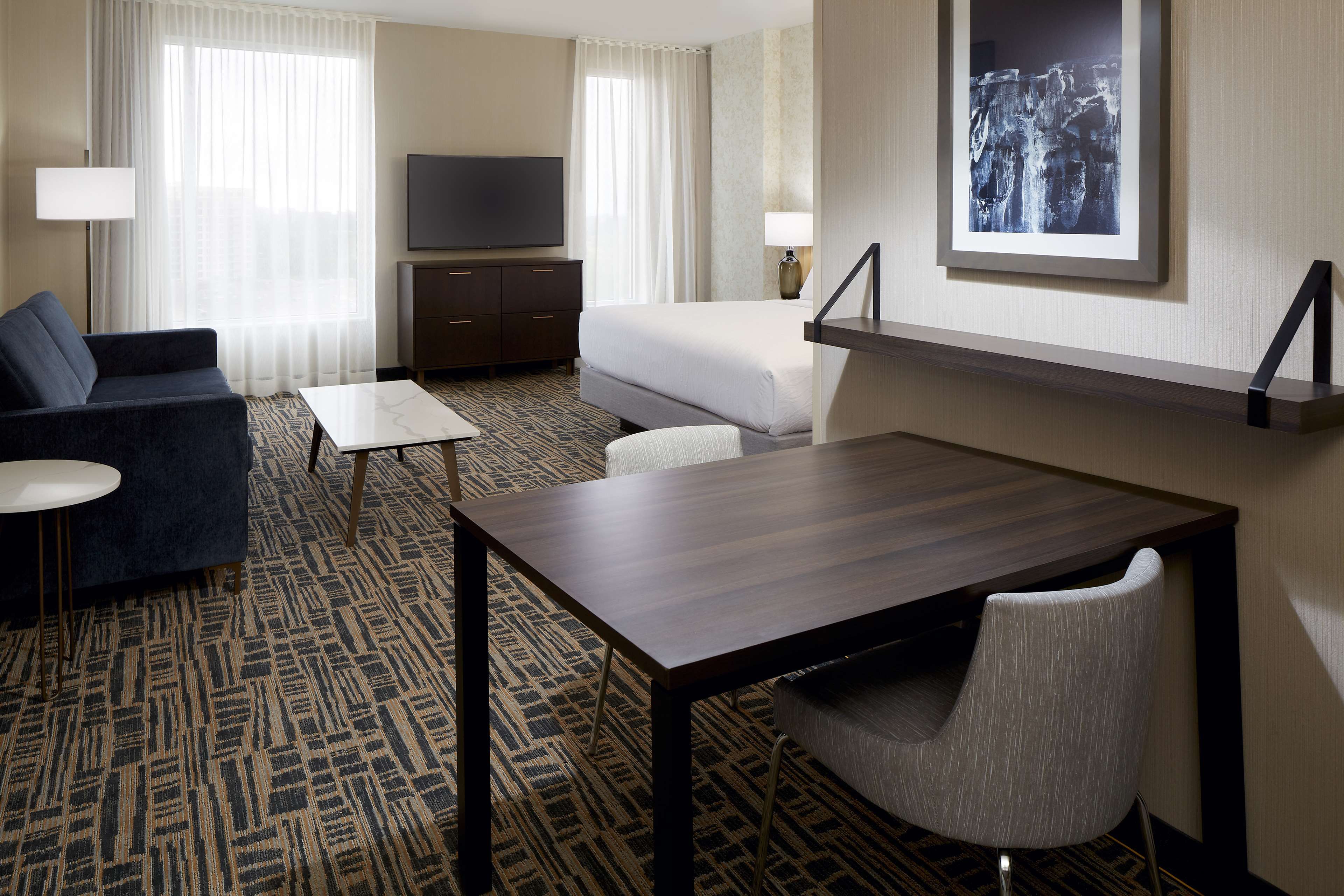 A hotel room with a bed, a sofa, a desk, and a television.