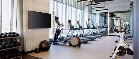 Un gimnasio con cintas de correr, pelotas de ejercicio y mancuernas.