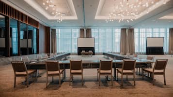 Une salle de conférence avec une longue table, des chaises et un grand écran.