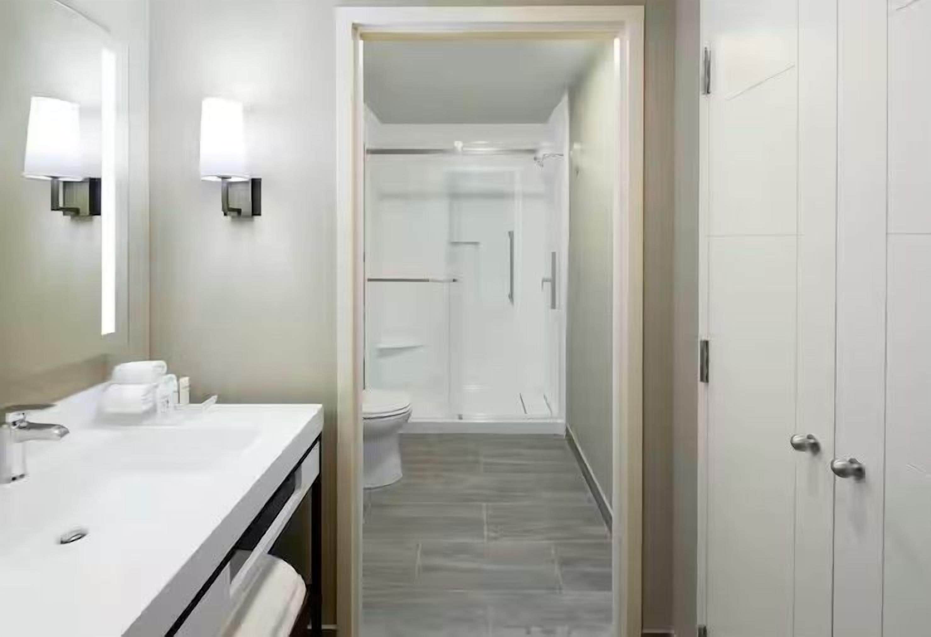 Un baño con lavamanos blanco, espejo y dos luces empotradas.