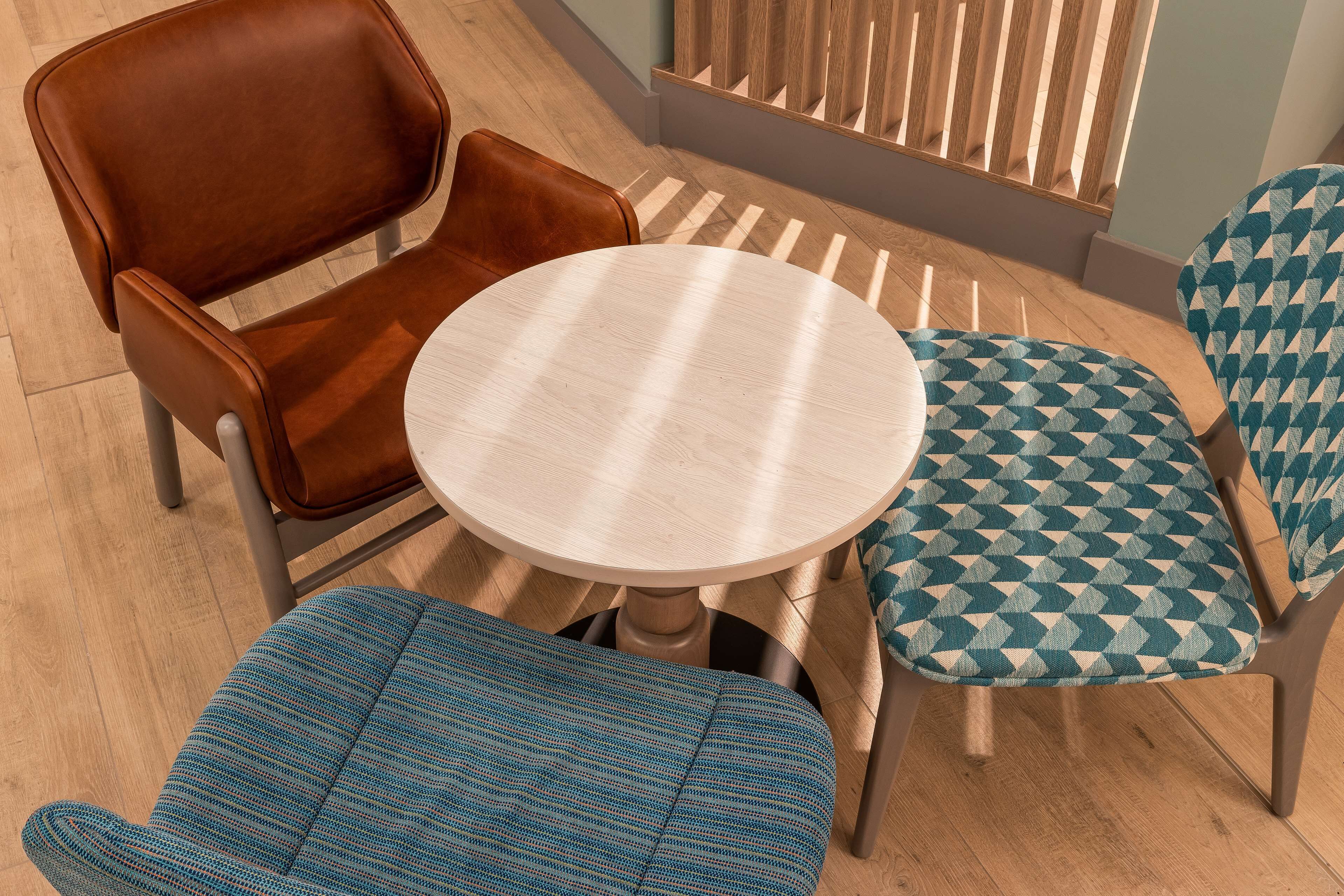 A dining area with a round table and four chairs, one of which is brown leather.