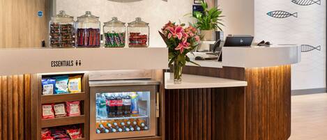 A reception desk with a coffee machine, a plant, and a wall with fish patterns.